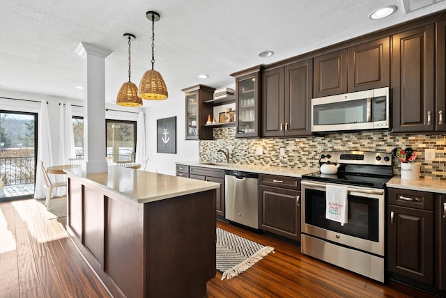 kitchen featuring a center island, dark brown cabinets, pendant lighting, stainless steel appliances, and backsplash