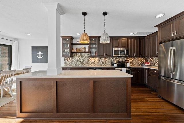 kitchen featuring stainless steel appliances, a kitchen island, hanging light fixtures, and dark brown cabinetry