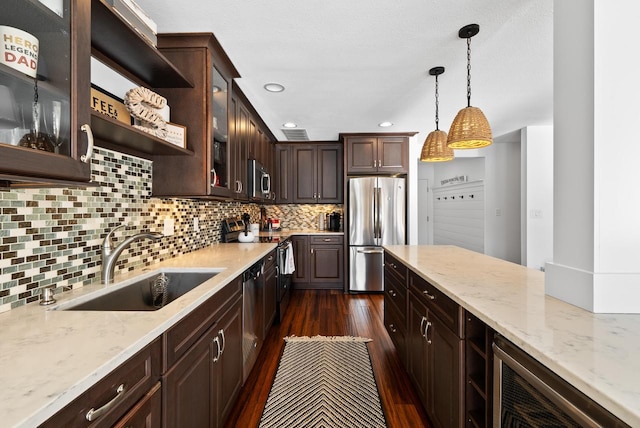 kitchen with pendant lighting, sink, backsplash, stainless steel appliances, and dark brown cabinets