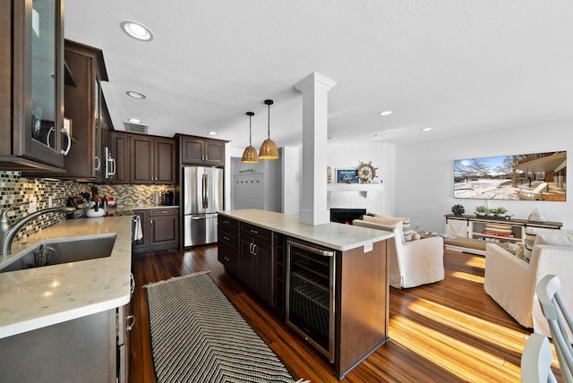 kitchen featuring sink, decorative light fixtures, dark brown cabinets, stainless steel fridge, and beverage cooler