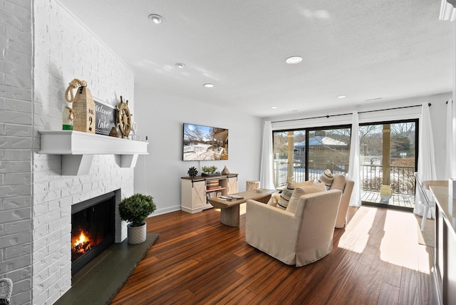 living room featuring a brick fireplace, dark hardwood / wood-style floors, and a textured ceiling