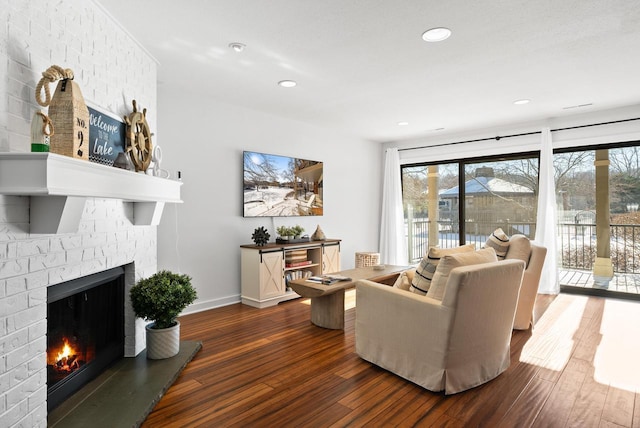 living room with a brick fireplace and dark hardwood / wood-style floors