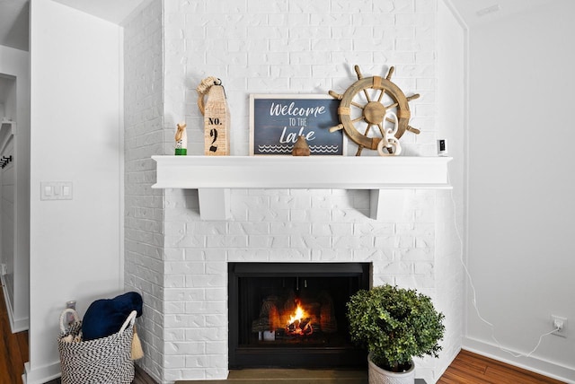 interior details featuring a brick fireplace and hardwood / wood-style floors