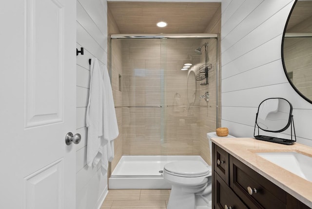 bathroom featuring wooden walls, vanity, toilet, and a shower with door