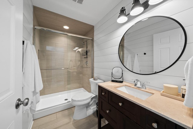 bathroom featuring vanity, toilet, an enclosed shower, and wood walls