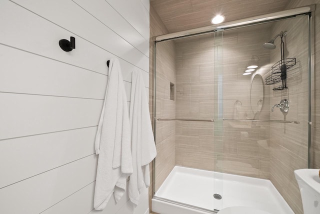 bathroom featuring wooden walls, toilet, and an enclosed shower