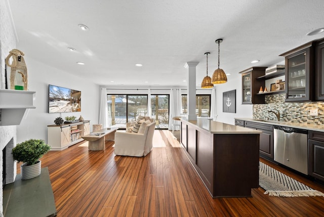 kitchen with backsplash, hanging light fixtures, a center island, stainless steel dishwasher, and dark brown cabinets