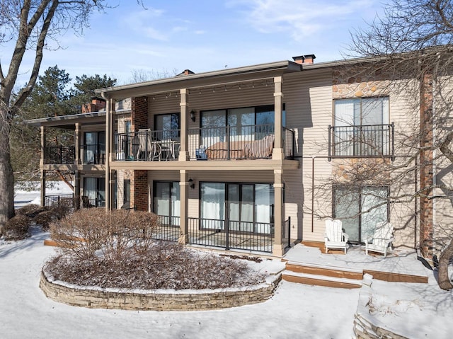 snow covered rear of property with a balcony