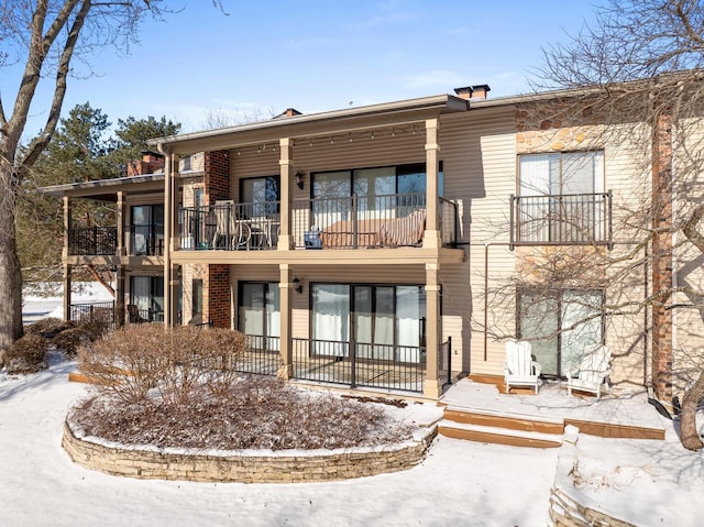 snow covered rear of property with a balcony