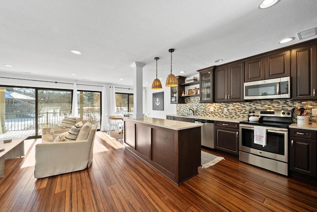 kitchen featuring hanging light fixtures, appliances with stainless steel finishes, a center island, and dark brown cabinetry