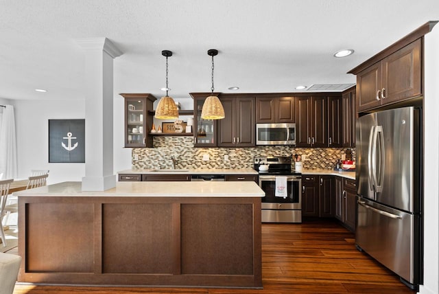 kitchen featuring dark brown cabinetry, hanging light fixtures, stainless steel appliances, and sink