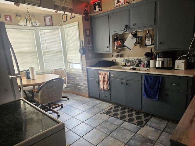 kitchen with gray cabinetry, sink, a chandelier, and white stove