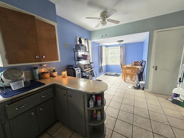 kitchen with light tile patterned floors, kitchen peninsula, and ceiling fan