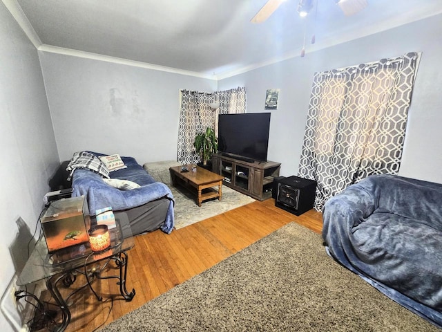 living room with wood-type flooring, ornamental molding, and ceiling fan