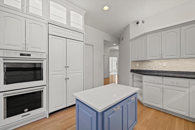 kitchen featuring tasteful backsplash, white cabinets, and double oven