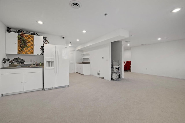 kitchen featuring white cabinetry, sink, white fridge with ice dispenser, and light carpet