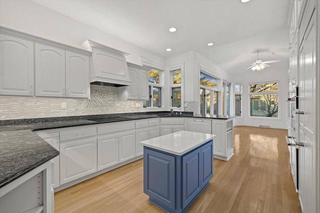 kitchen with tasteful backsplash, light hardwood / wood-style floors, a kitchen island, and white cabinets