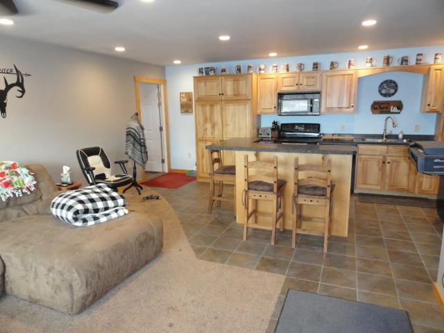 N8621 5th Rd, Westfield, WI 53964 - kitchen featuring sink, dark tile patterned floors, stove, a kitchen bar, and light brown cabinetry