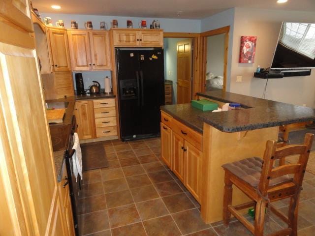 N8621 5th Rd, Westfield, WI 53964 - kitchen with black fridge, a kitchen breakfast bar, light brown cabinetry, and a kitchen island