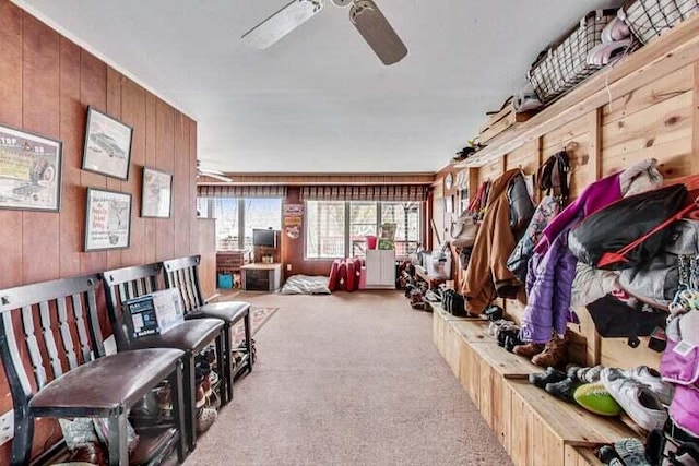 mudroom with ceiling fan, light colored carpet, and wood walls