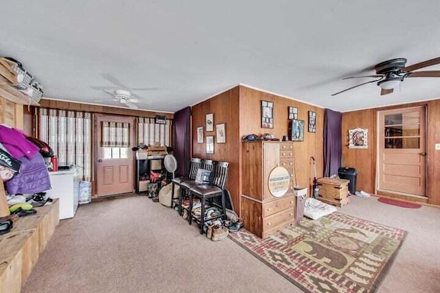 interior space featuring wooden walls, light carpet, and ceiling fan