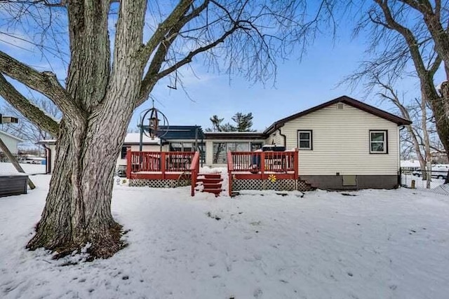 snow covered back of property featuring a wooden deck