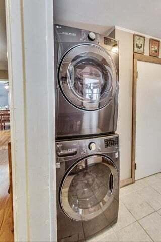 washroom with stacked washer / dryer and light tile patterned floors