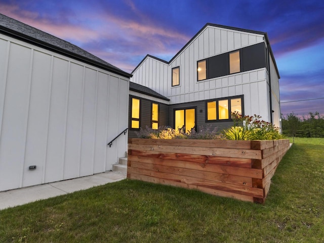 back house at dusk featuring a lawn