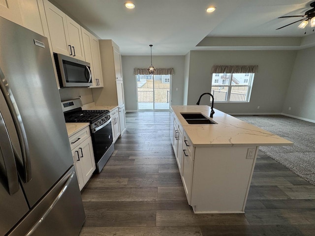 kitchen with stainless steel appliances, a center island with sink, and white cabinets