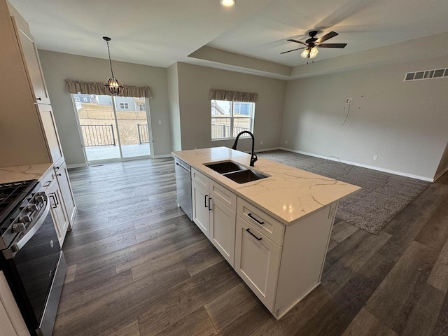 kitchen with a kitchen island with sink, white cabinetry, hanging light fixtures, stainless steel appliances, and light stone counters