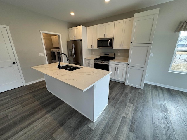 kitchen featuring white cabinetry, appliances with stainless steel finishes, light stone counters, and a center island with sink