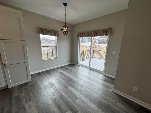 unfurnished dining area with dark wood-type flooring and an inviting chandelier