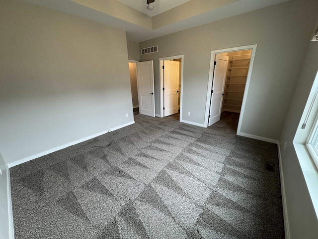 unfurnished bedroom with a walk in closet, carpet flooring, and a closet