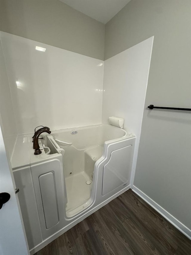 bathroom with hardwood / wood-style flooring and a tub