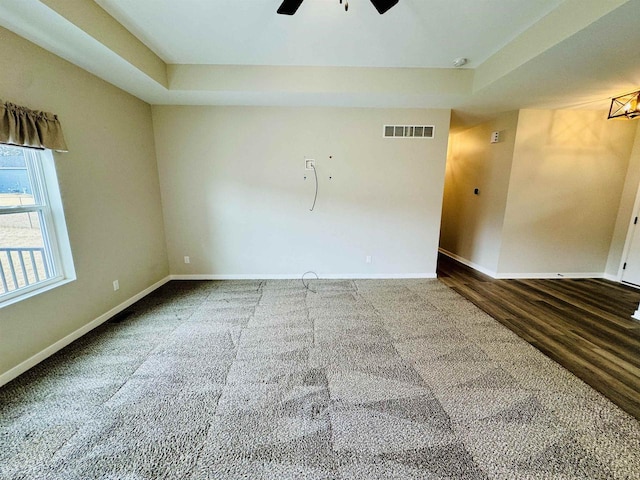 unfurnished room with wood-type flooring, a raised ceiling, and ceiling fan