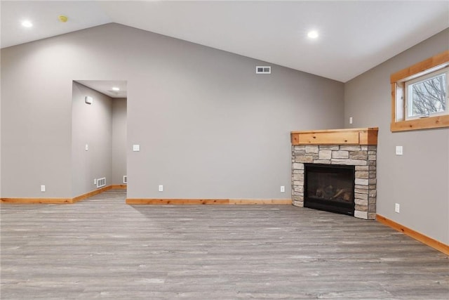 unfurnished living room with a fireplace, vaulted ceiling, and light wood-type flooring