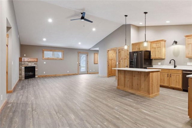 kitchen featuring light brown cabinetry, hanging light fixtures, a kitchen island, and black fridge