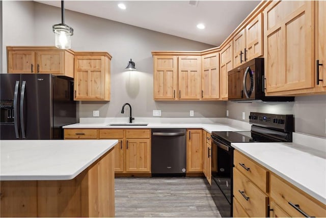 kitchen featuring lofted ceiling, sink, decorative light fixtures, light wood-type flooring, and black appliances