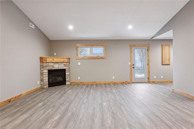 unfurnished living room with vaulted ceiling, plenty of natural light, light wood-type flooring, and a fireplace