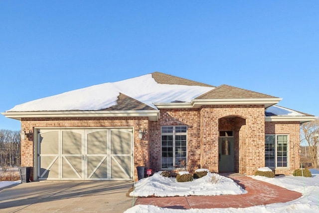 view of front facade featuring concrete driveway, brick siding, and an attached garage