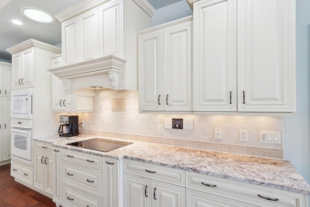 kitchen with white cabinets, premium range hood, black electric cooktop, and decorative backsplash