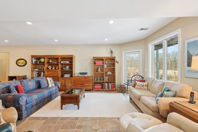 living room featuring stone finish floor, visible vents, and recessed lighting