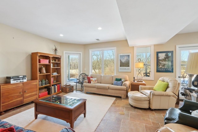 living room with recessed lighting, stone finish floor, a healthy amount of sunlight, and visible vents