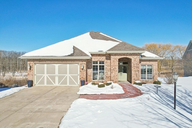 view of front facade with a shingled roof, concrete driveway, brick siding, and an attached garage