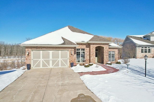 view of front of house with driveway, brick siding, an attached garage, and a shingled roof