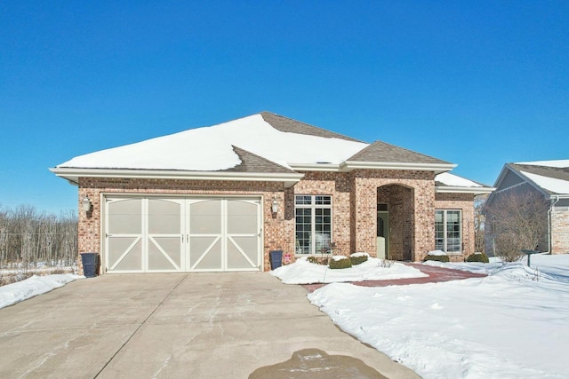 view of front of home with driveway, brick siding, an attached garage, and a shingled roof