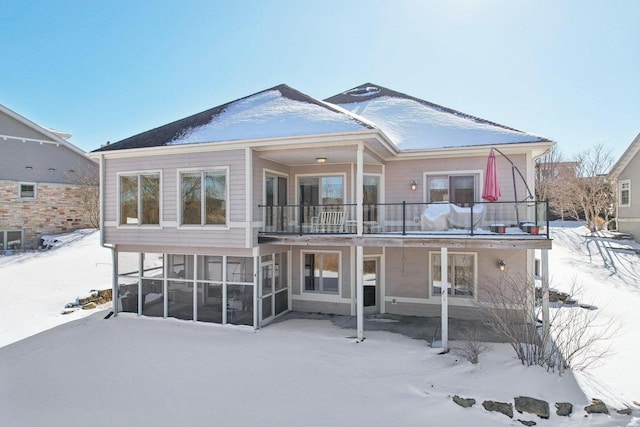 snow covered property featuring a sunroom and a balcony