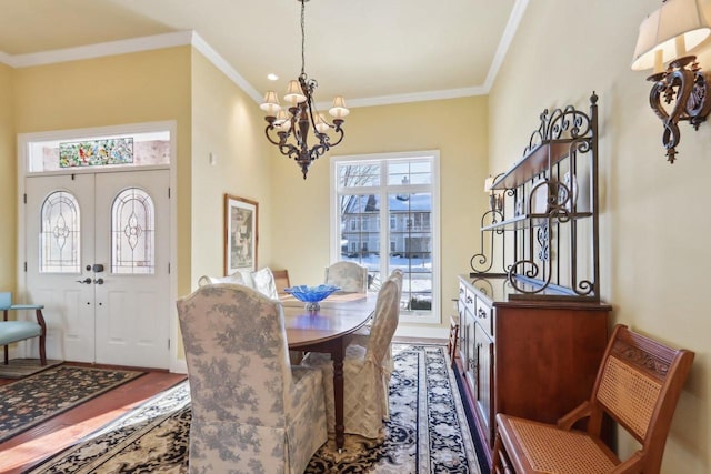 dining space with french doors, ornamental molding, wood finished floors, and a notable chandelier