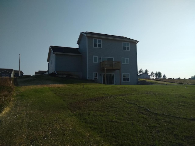 rear view of property with a balcony and a lawn