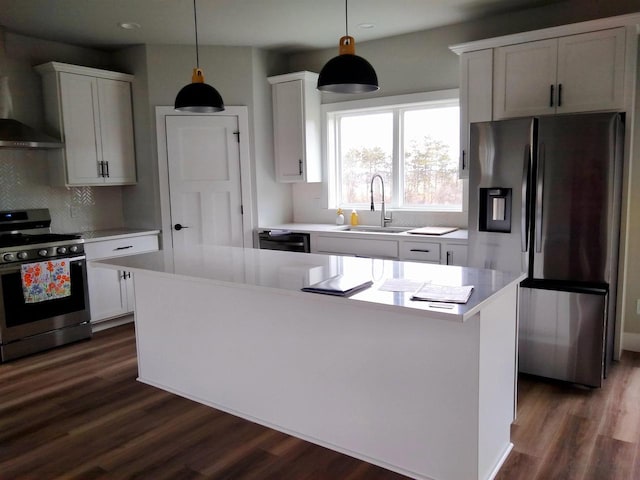 kitchen with a center island, stainless steel appliances, hanging light fixtures, white cabinets, and a sink